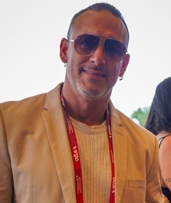 Rocco Generoso Jr (Rock) in a tan blazer and sunglasses with a red lanyard