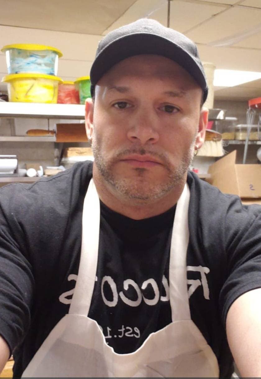 Rocco Generoso Jr (Rock) in a bakery kitchen wearing a cap and apron